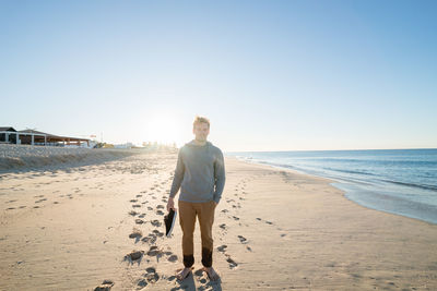 Portrait of man standing at beach against sky