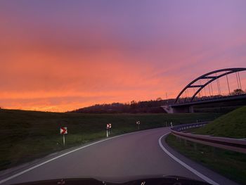 Road by bridge against sky during sunset