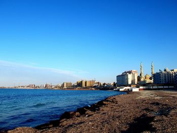 View of sea and buildings against blue sky