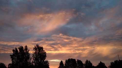 Low angle view of silhouette trees against dramatic sky