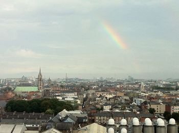 Rainbow over cityscape against sky