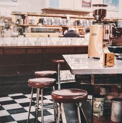 Coffee maker on table by seats in cafe