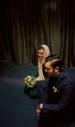 High angle view of couple holding bouquet while kneeling on floor