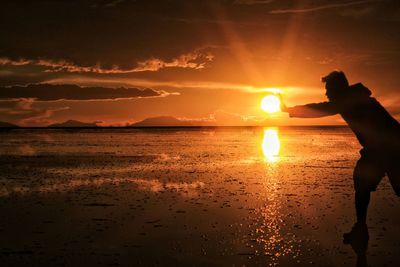 Silhouette man at beach against sky during sunset