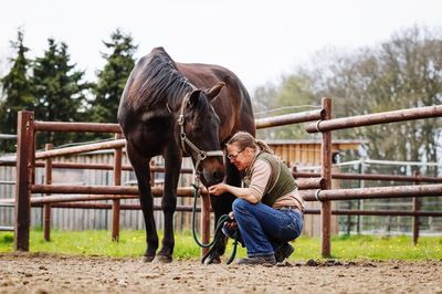 Side view of woman with horse on field