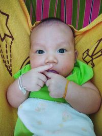 Portrait of cute baby girl lying on bed