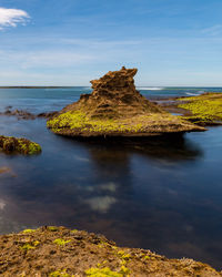 Rock formation on sea shore against sky