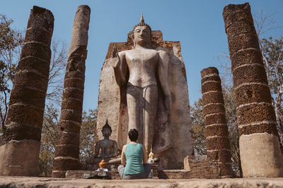 Rear view of woman looking at buddha statue