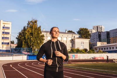 Woman running in stadium against sky