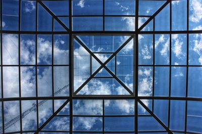 Low angle view of glass window against blue sky