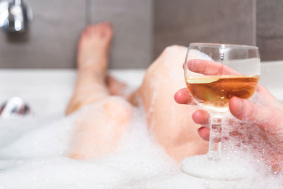 Midsection of woman in drinking glass at home