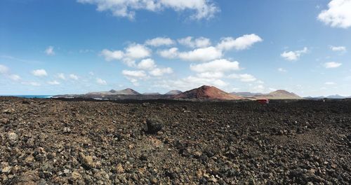 Scenic view of desert against cloudy sky on sunny day