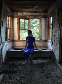 Full length of woman sitting in abandoned room