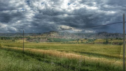 Scenic view of grassy field against cloudy sky