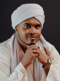 Portrait of young man wearing hijab against black background