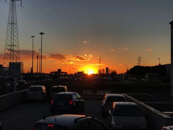 Cars on road in city against sky during sunset