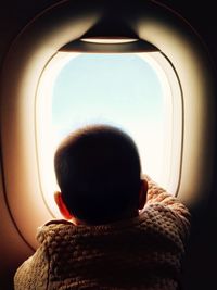 Rear view of man looking at airplane window
