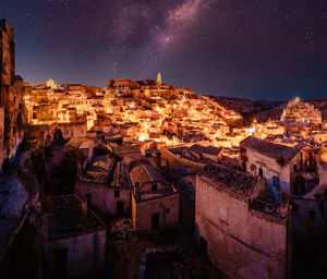 Panorama of matera from piazzetta pascoli at night with illuminated houses and starry sky