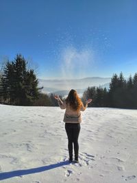 Rear view of woman walking in snow against clear sky