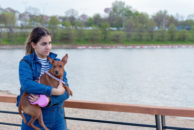 A teen girl holding a miniature pincher in her arms by the of relationship between human and animal.