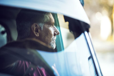 Thoughtful man sitting in car seen through windshield