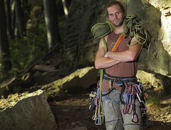 Rock climber posing with climbing rope on his shoulders