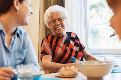 Happy senior woman talking to daughter at dining table