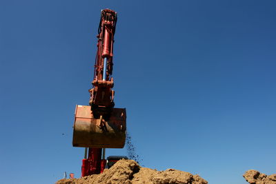 Low angle view of construction site against clear blue sky