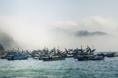 Fishing boats in sea against sky