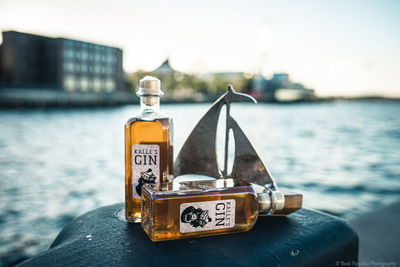 Close-up of bottle by sea against sky in city