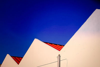 Low angle view of flags against clear blue sky