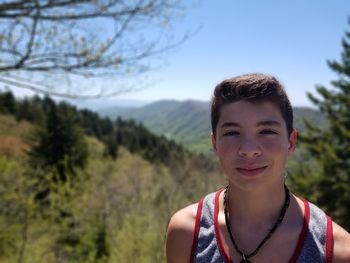 Portrait of teenage boy smiling against trees