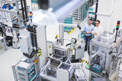 Two men with tablet talking in factory shop floor