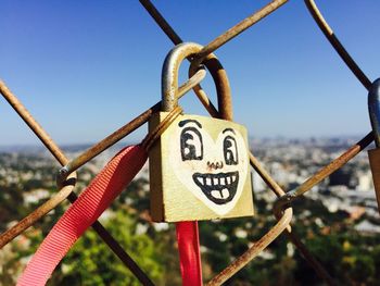 Face drawn on padlock attached to chainlink fence