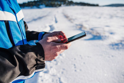 Man holding using smart phone snow covered land