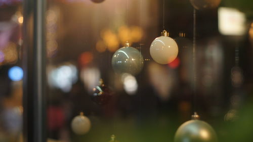 Close-up of christmas lights hanging on glass window