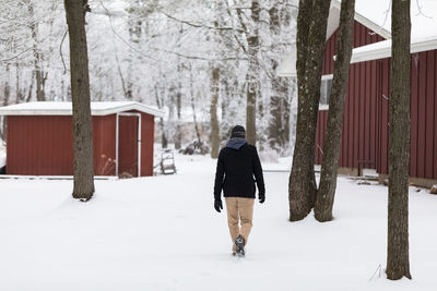 Rear view of man walking on snow covered land