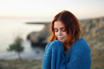 Beautiful young woman looking at sea against sky