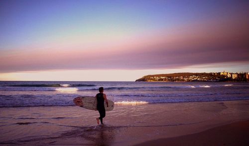 Man on beach against sky during sunset