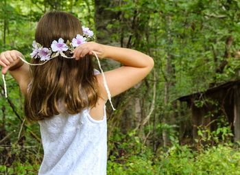 Rear view of girl wearing flowers against trees