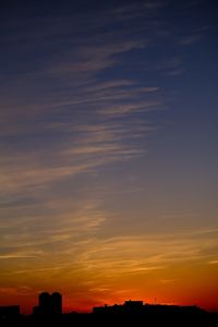 Silhouette buildings against dramatic sky during sunset