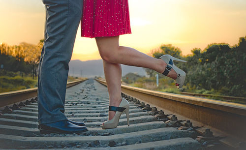 Low section of couple standing on railroad track