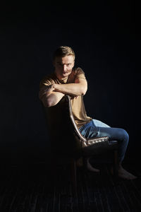 Handsome young man in t-shirt and jeans alone in dark