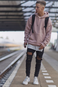 Young man standing at railroad station platform