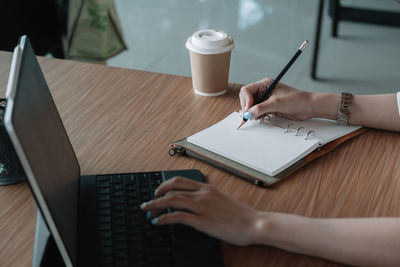 Midsection of woman with coffee cup on table