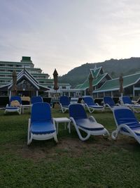 Deck chairs on grass against sky