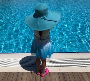 Rear view of woman standing by swimming pool
