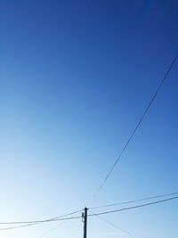 Low angle view of power lines against clear blue sky