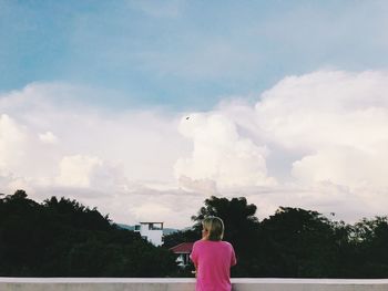 Rear view of woman looking at trees against sky