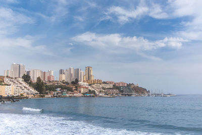 Sea by buildings against sky in city